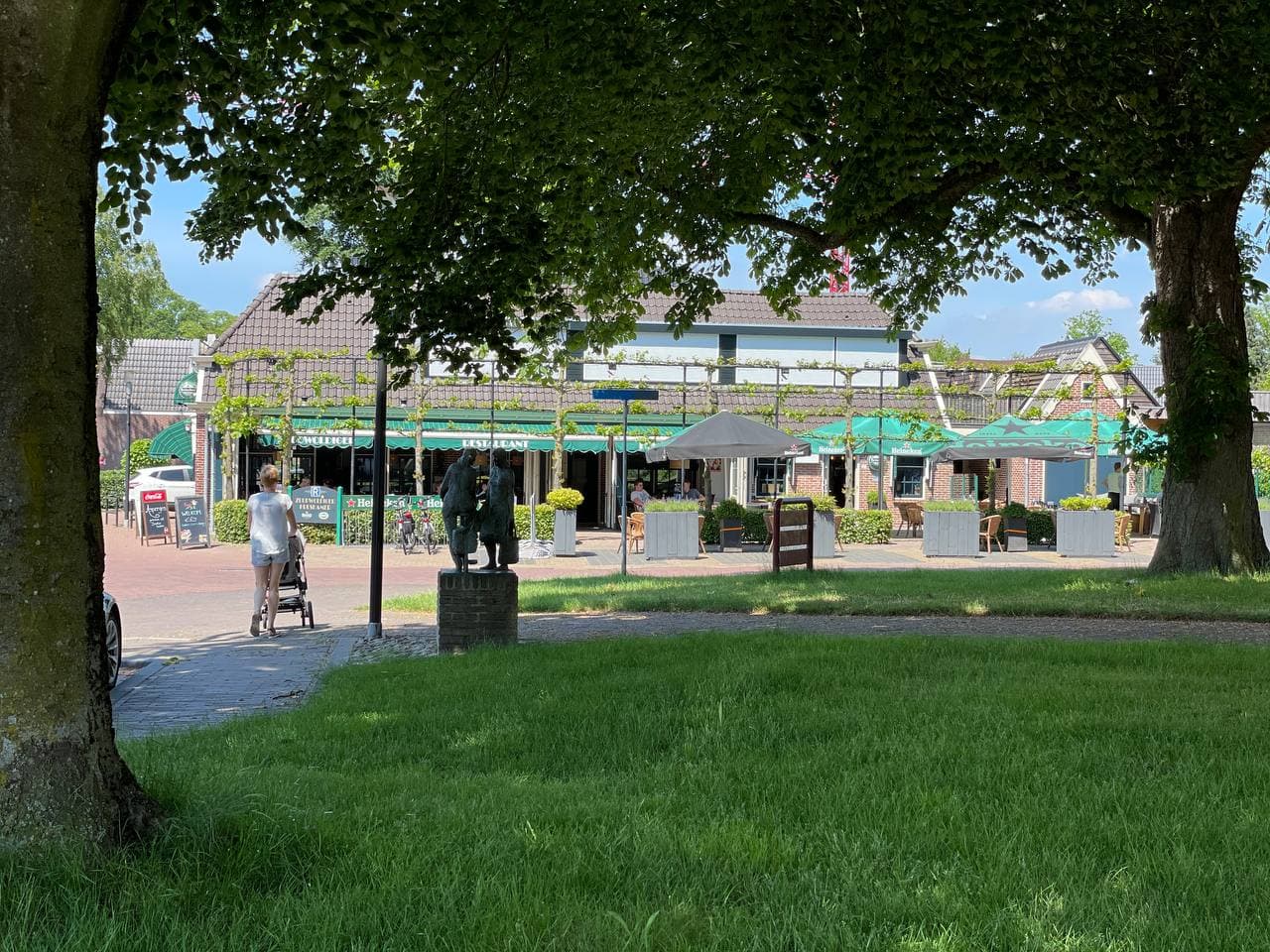 Gezellig dorpsplein met terrassen en standbeeld